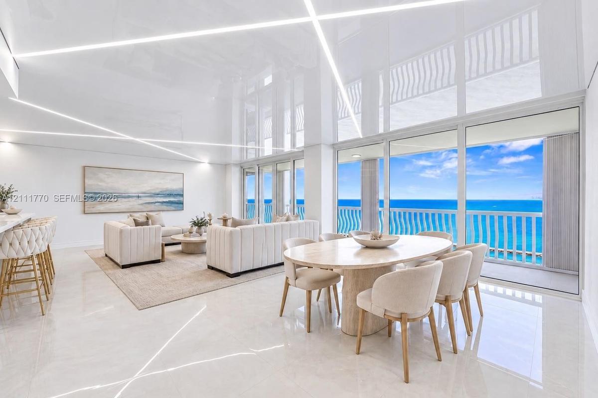 High-gloss reflective ceiling with integrated linear LED lighting, polished stone flooring, and expansive floor-to-ceiling glass sliding doors opening