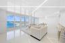 Open-concept space featuring high-gloss ceilings with recessed linear lighting, polished tile flooring, and floor-to-ceiling sliding glass doors openi