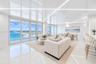High-gloss ceiling with integrated linear lighting, large-format tile flooring, and expansive floor-to-ceiling glass sliding doors opening to a balcon