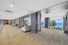 Expansive common area featuring wood-finish flooring, floor-to-ceiling windows with ocean scenery, dark wood-tone architectural columns, and recessed 