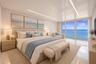 High-gloss ceiling with recessed linear lighting, polished tile flooring, and large-format glass sliding doors opening to a balcony with ocean scenery