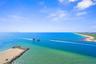 Aerial perspective featuring a stone jetty, expansive sandy shoreline, and direct ocean access
