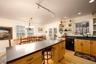 Kitchen with light wood-style floors, black dishwasher, rail lighting, a kitchen breakfast bar, and open shelves