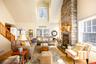 Living room with hardwood / wood-style flooring, a stone fireplace, and a high ceiling