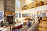 Living area featuring light wood-type flooring, healthy amount of natural light, a fireplace, and a high ceiling