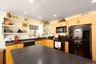 Kitchen with black appliances, light wood finish cabinets, recessed lighting, open shelves, and dark stone countertops