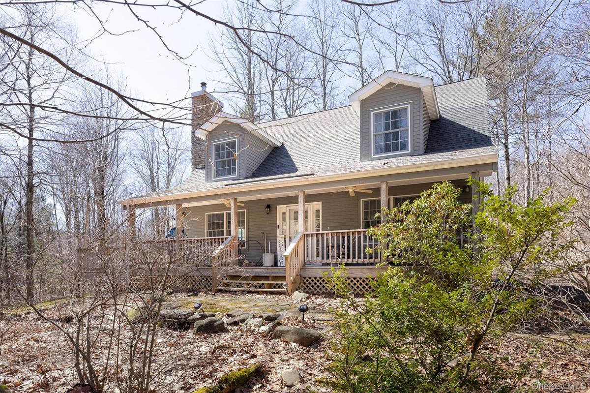 View of front of home with roof with shingles, a porch, and a chimney