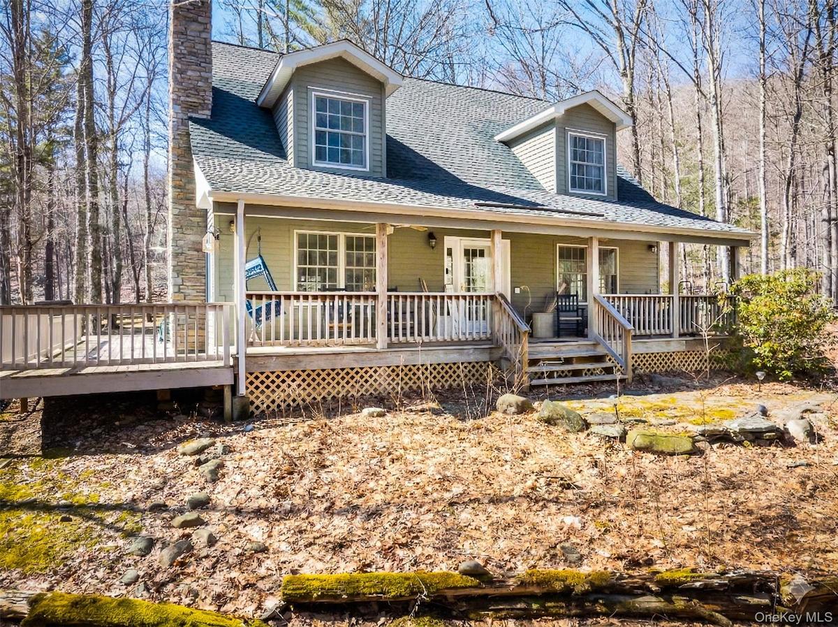Cape cod home featuring roof with shingles, a porch, and a chimney