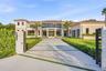 Modern estate featuring a structured concrete driveway with turf ribbons, a multi-story facade with expansive floor-to-ceiling glass paneling, tile ro