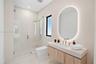 Floating vanity featuring a wood-finish cabinet and integrated countertop, complemented by an oval-shaped LED backlit mirror