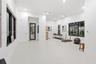 Spacious interior featuring high ceilings, recessed lighting, large windows with dark frames, smooth-finish flooring, and a glass-paneled door