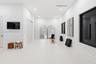 Spacious room featuring high ceilings, recessed lighting, smooth-finish solid flooring, and multiple large windows with dark trim