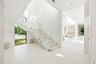 Open-riser staircase with stone treads and frameless glass railing, polished stone flooring, and expansive windows