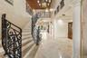 Foyer featuring stone flooring, a decorative patterned ceiling, an ornamental wrought iron staircase railing, and architectural columns