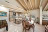 Vaulted ceilings with decorative exposed beams, polished stone flooring, central kitchen island with integrated wine storage, and ornate multi-arm cha