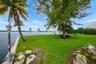 Waterfront lawn featuring mature trees, natural stone accents, and a classic metal post lantern