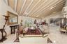Vaulted ceiling with decorative wood beams, stone flooring, recessed lighting, and ornate staircase with decorative metal railing