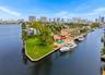 Waterfront property featuring a concrete seawall, expansive lawn, swimming pool, and stone-paved patio