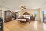 Spacious room featuring wood-finish flooring, crown molding, a central ceiling fan with integrated lighting, and glass sliding doors