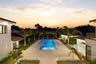 Rectangular swimming pool with integrated sun shelf, expansive stone-paved patio, glass panel perimeter railing, and mature palm landscaping