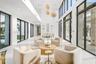 Double-height ceilings, floor-to-ceiling black-framed windows, multi-tiered orb pendant lighting, glass-paneled mezzanine railing, and integrated wall