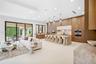 Open-concept living space featuring wood-finish cabinetry, a large waterfall-edge kitchen island, recessed ceiling lighting, and expansive multi-panel