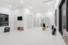 Spacious room featuring high ceilings, recessed lighting, polished concrete-finish flooring, and large windows with dark-finish frames