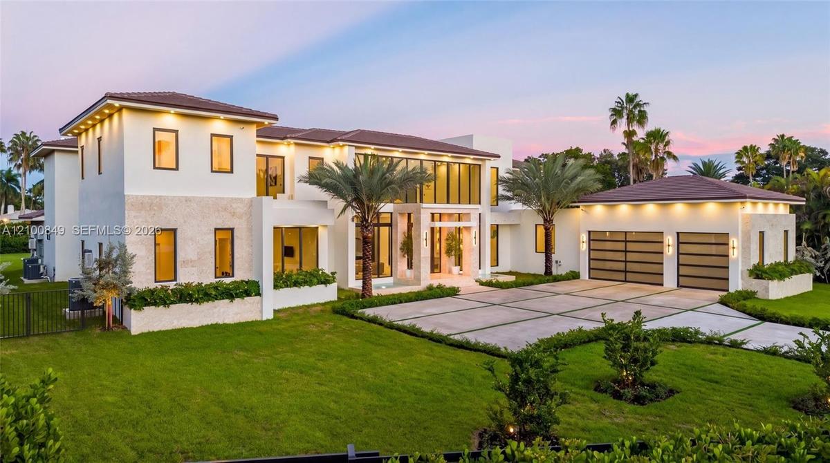 Modern exterior featuring smooth-finish stucco, stone veneer accents, multi-pane floor-to-ceiling windows, a tiled hipped roof, and a segmented concre