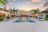 Contemporary estate exterior featuring a sprawling limestone pool deck, rectangular swimming pool with integrated stepping stones, multi-wing architec
