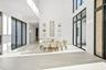 Double-height ceiling, large-format tile flooring, floor-to-ceiling black-framed windows, and built-in wall niches
