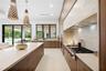 Modern kitchen featuring flat-panel wood cabinetry, a large central island with solid-surface countertops, professional-grade gas cooktop, and decorat