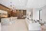 Custom kitchen cabinetry, stone-clad waterfall island, integrated refrigeration, built-in wine storage, and three textured pendant lights