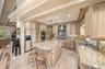 Kitchen featuring custom cabinetry with detailed millwork, stone countertops, a central island, recessed lighting, and stainless steel appliances