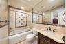 Bathroom featuring a custom wood vanity with stone countertop, undermount sink, brass-finished faucet, and large wall-to-wall mirror