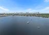 Aerial perspective featuring an expansive coastal waterway with moored watercraft and a distant city skyline