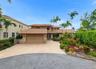 Multi-level exterior featuring a tile roof, stone masonry accents, a paved circular driveway, and mature landscaping