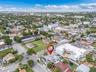 Aerial perspective of a corner lot property featuring a hip roof structure, paved driveway, and established perimeter fencing