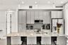 Kitchen featuring flat-panel cabinetry, a stone-surfaced kitchen island, stainless steel appliances, and glass pendant lighting