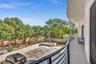 Curved exterior balcony featuring metal railings, smooth stucco wall, and concrete flooring