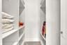 Custom reach-in storage system with white finish, adjustable shelving, integrated garment rods, and large-format tile flooring