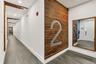 Hallway featuring large-format tile flooring, horizontal wood-slat accent wall, integrated recessed ceiling lighting, and wood-framed mirror