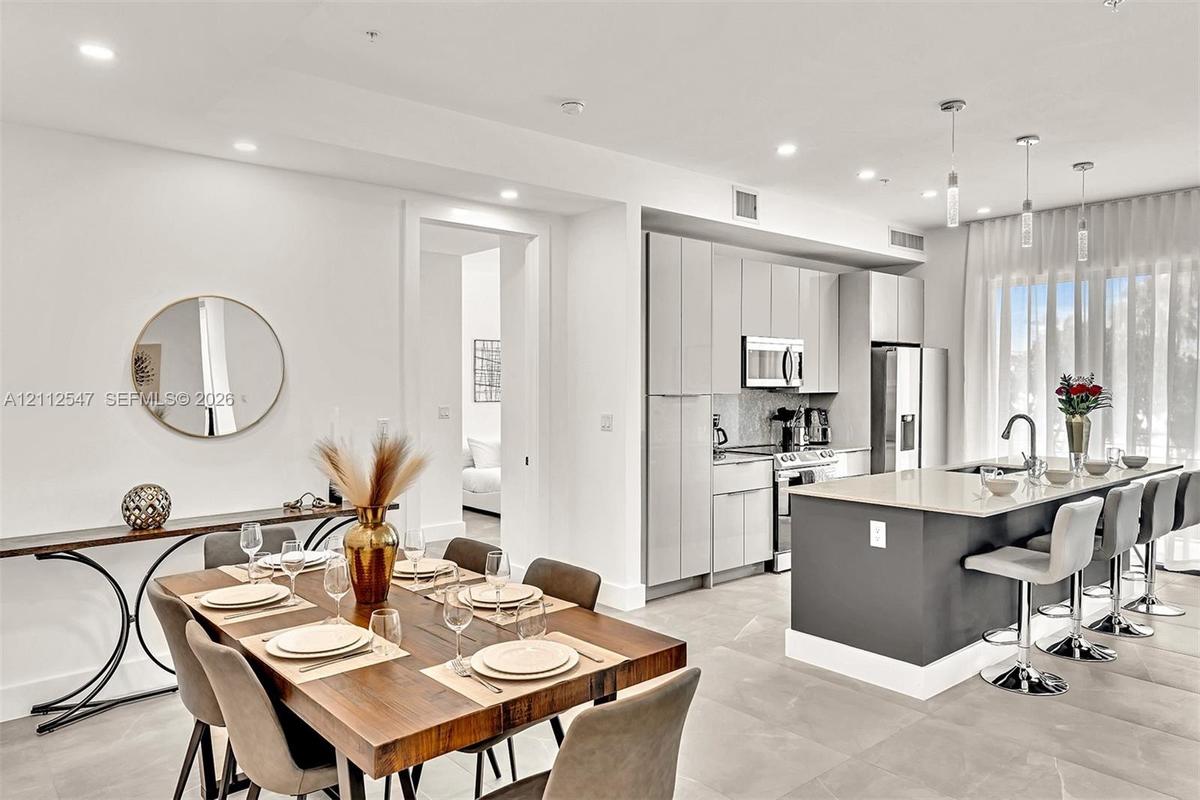 Kitchen featuring slab-front cabinetry, a quartz-topped center island with bar seating, stainless steel appliances, recessed lighting, and large-forma