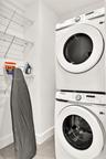 Laundry area featuring a stacked front-loading washer and dryer with integrated white wire shelving