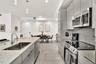 Kitchen featuring high-gloss cabinetry, stone-finish countertops, stainless steel appliances, large-format floor tile, and pendant lighting
