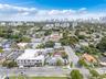 Aerial perspective of urban neighborhood featuring high-rise city skyline, paved street infrastructure, and established greenery