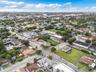 Aerial perspective of the neighborhood featuring varied residential architecture, established tree canopy, and paved street access