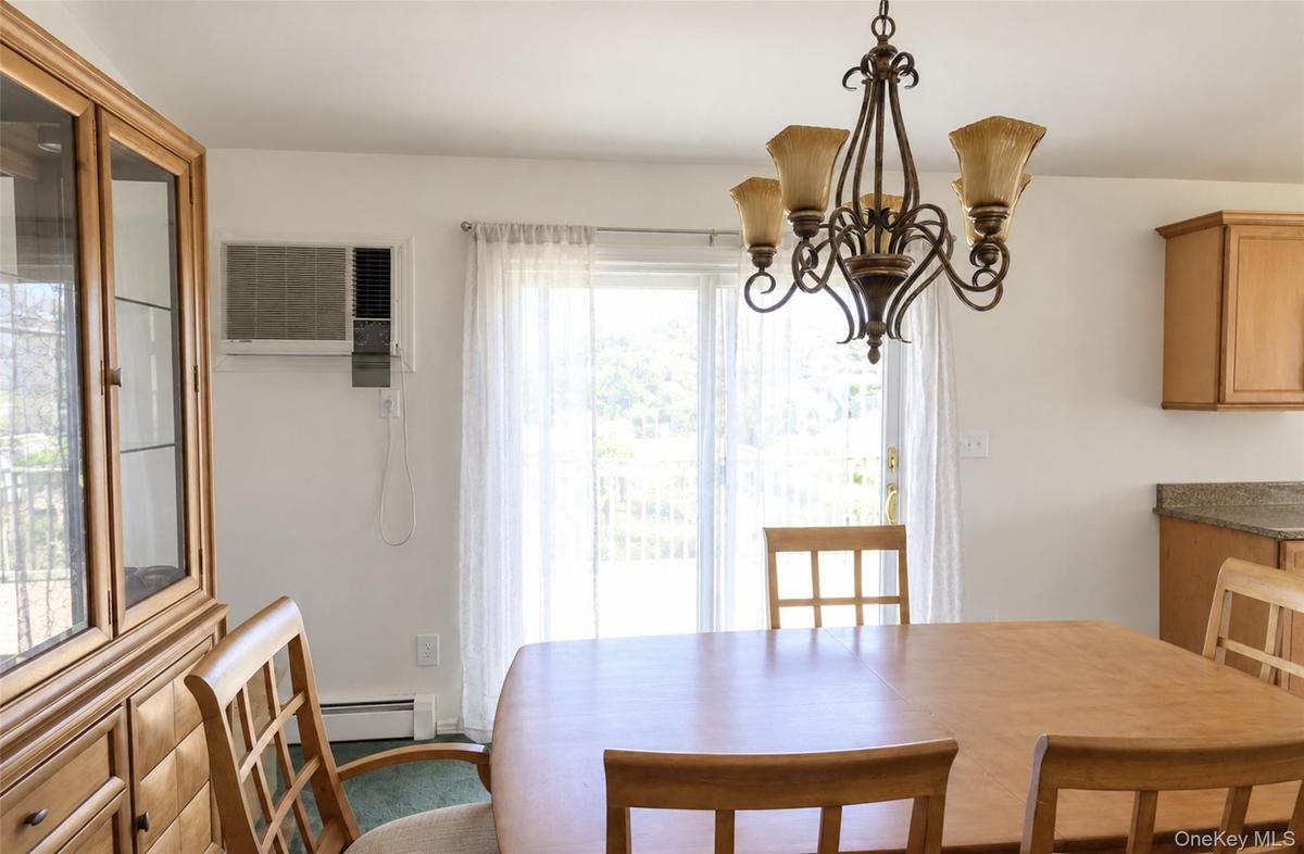 Dining area featuring a decorative wrought-iron chandelier, built-in wooden cabinetry, and sliding glass doors