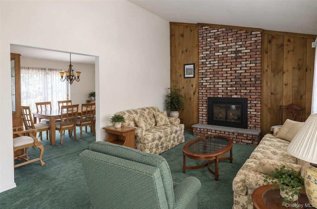 Vaulted ceilings, floor-to-ceiling brick fireplace with stone hearth, and natural wood-paneled accent wall