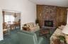 Vaulted ceilings, floor-to-ceiling brick fireplace with stone hearth, and natural wood-paneled accent wall
