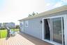 Exterior featuring gray shingle siding, a composite deck, white gutters, and a sliding glass door